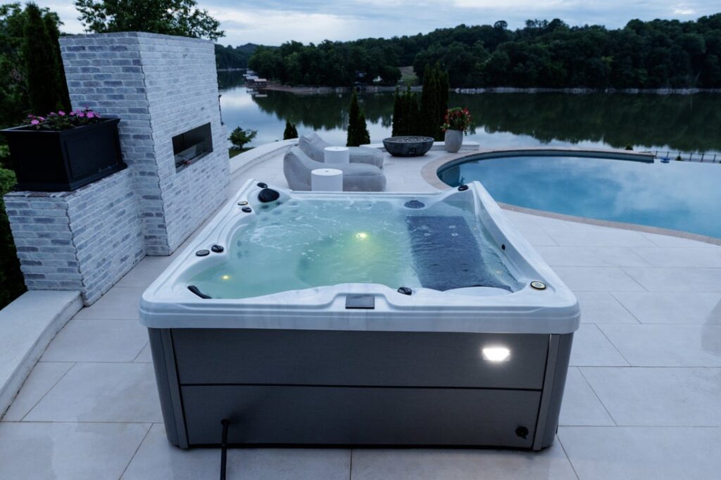 Outdoor hot tub with lit hydrotherapy jets overlooking a lake at twilight
